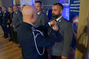 policjant przypina do munduru funkcjonariusza medal
