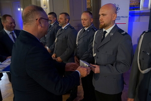 przedstawiciel Narodowego Banku Polskiego wręcza policjantowi limitowany banknot 20 złotowy