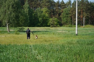 Policjant z psem na łące w czasie zawodów.