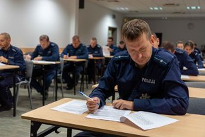 policjanci siedzą w ławkach i piszą test