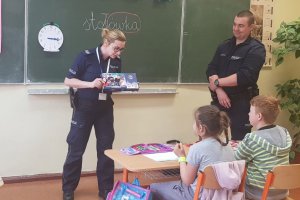 Policjanci pokazują dzieciom grę edukacyjną dotyczącą zasad ruchu drogowego