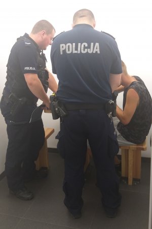 policjanci wykonujący czynności z zatrzymanym