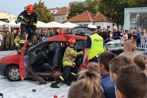 Strażacy i policjanci wykonujący czynności na miejscu wypadku drogowego. Strażacy rozcinają dach auta biorącego udziała w zdarzeniu.