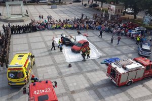 Zdjęcie zrobione z góry przedstawiające płytę chełmińskiego Rynku, podczas pokazów współdziałania służb ratowniczych. Na fotografii widać rozmieszczenie pojazdów oraz osób biorących udział w wydarzeniu.