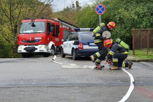 Strażacy rozwijają wąż podczas ćwiczeń dowódczo-sztabowych