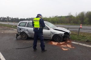 Policjant wykonujący oględziny samochodu biorącego udział w zdarzeniu drogowym