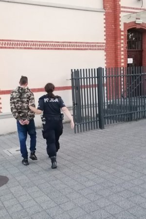 policjantka prowadzi zatrzymanego mezczyzne