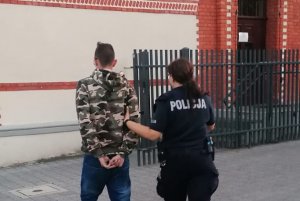 policjantka prowadzi zatrzymanego do jednostki policji