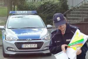 policjantka pokazuje dzieciom elementy odblaskowe i książeczki edukacyjne