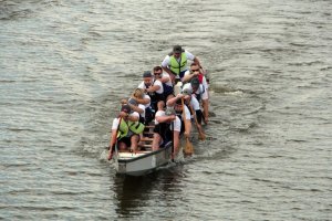 zawodnicy płyną smoczą łodzią