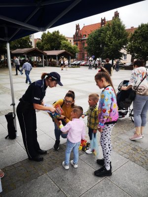 policjantka wręcza dzieciom kolorowanki