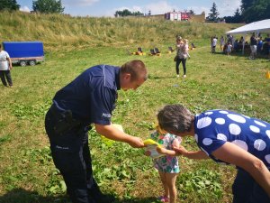 policjant wręcza dziecku kamizelkę odblaskową