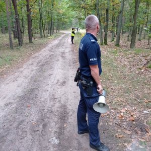 umundurowany policjant stoi w kordonie z megafonem w ręku