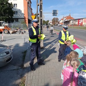 policjanci wręczają dzieciom kamizelki odblaskowe