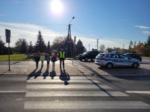 policjant i dzieci stoją przy przejściu dla pieszych