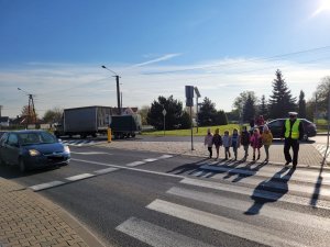 policjant z dziećmi przechodzą przez jezdnię