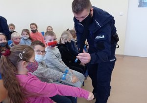 policjant wręcza dziecku odblask