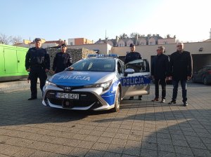 policjanci i samorządowcy pozują przy radiowozie