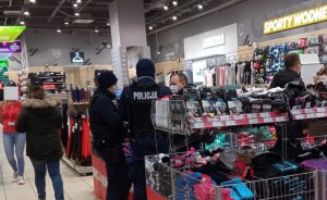 policjanci legitymują mężczyznę w obiekcie handlowym