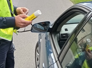 policjant trzyma w ręku urządzenie do sprawdzania stanu trzeźwości