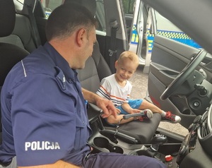 policjant i chłopiec siedzą w radiowozie policyjnym