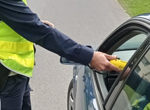 policjant sprawdza stan trzeźwości kierowcy urządzeniem bezustnikowym