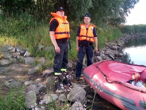 policjant i strażak pozują do zdjęcia przy pontonie strażackim