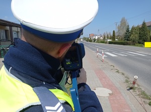 policjant ruchu drogowego mierzy prędkość jadącego pojazdu