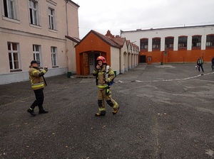 strażacy stoją przed budynkiem szkoły