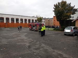 policjanci i strażacy stoją przed budynkiem szkoły