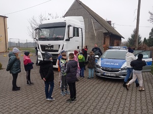 dzieci i dorośli stoją przy ciężarówce i radiowozie