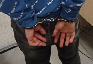 zatrzymany ma założone kajdanki na ręce trzymane z tyłu