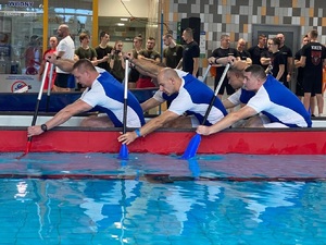zawodnicy w łodzi umieszczonej w basenie