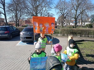 dzieci stoją na parkingu z kolorowymi plakatami