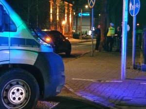 policyjny furgon stoi na jezdni w rejonie przejścia dla pieszych w tle widać stojącego policjanta w kamizelce odblaskowej