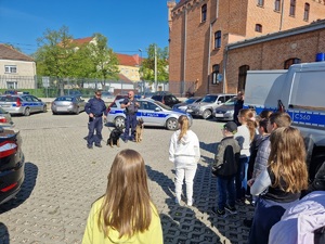 przewodnicy psów służbowych z psami stoją przed dziećmi