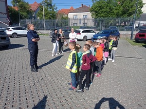 policjantka rozmawia z dziećmi stojącymi przed nią