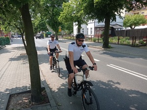 policjanci na rowerach jadą ulicą