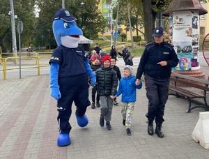 Polfin i policjantka idą z dziećmi chodnikiem