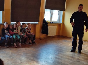 policjant stoi i opowiada dzieciom o swojej pracy