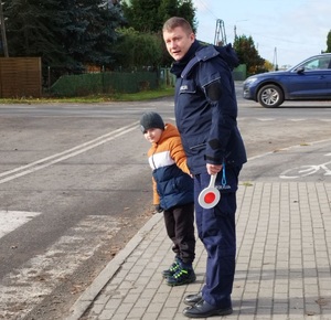 policjant z chłopcem stoją przy przejściu dla pieszych