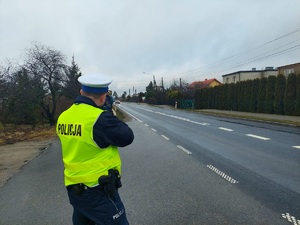 policjant kontroluje prędkość jadących pojazdów ręcznym miernikiem prędkości