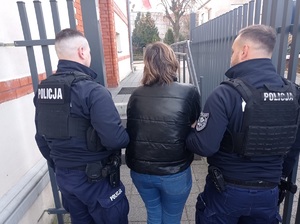 umundurowani policjanci prowadza zatrzymana kobietę