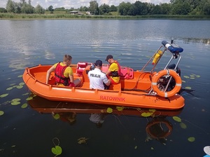 ratownicy i policjant płyną łodzią motorową