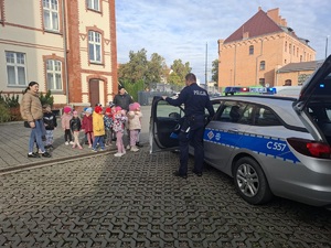 policjant pokazuje dzieciom policyjny radiowóz