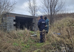 policjant i kobieta stoją obok opuszczonego budynku