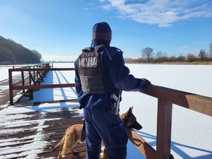 policjant obserwuje z pomostu zamarznięte jezioro