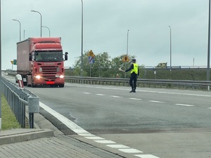 policjant ruchu drogowego zatrzymuje do kontroli samochód ciężarowy