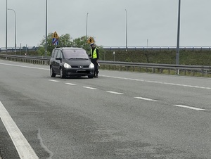 policjant ruchu drogowego kontroluje trzeźwość kierującego samochodem osobowym