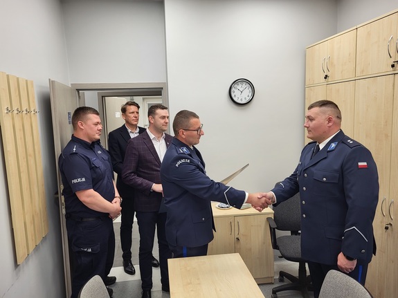 komendant wręcza rozkaz policjantowi w obecności zaproszonych gości